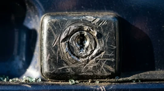 Vue détaillée d'une serrure de voiture endommagée avec des marques d'effraction et une vitre latérale brisée