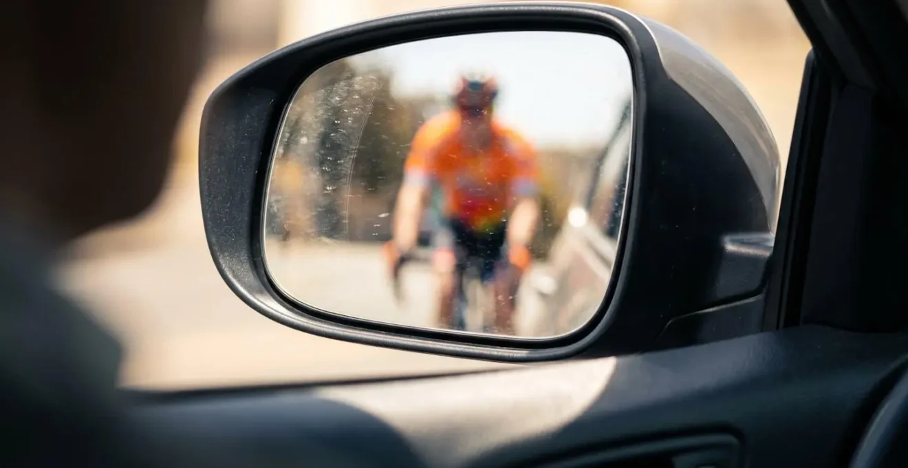 Conducteur vérifiant son angle mort avec cycliste visible dans le rétroviseur